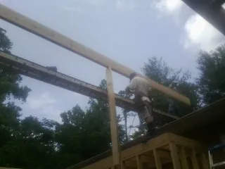 Carpenter setting a ridge beam over a new addition frame — Ice Dam Removal by Roofing Brothers in Sachse