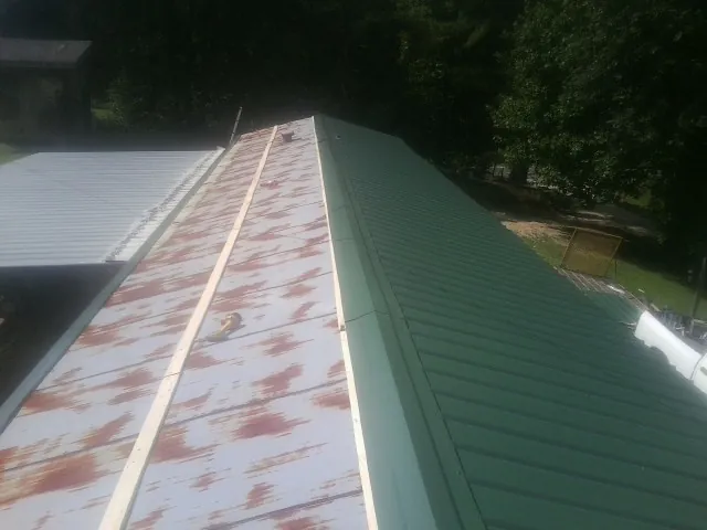 Old rusted panels beside newly installed green metal roofing — Wind Damage Roof Repair by Roofing Brothers in Sachse