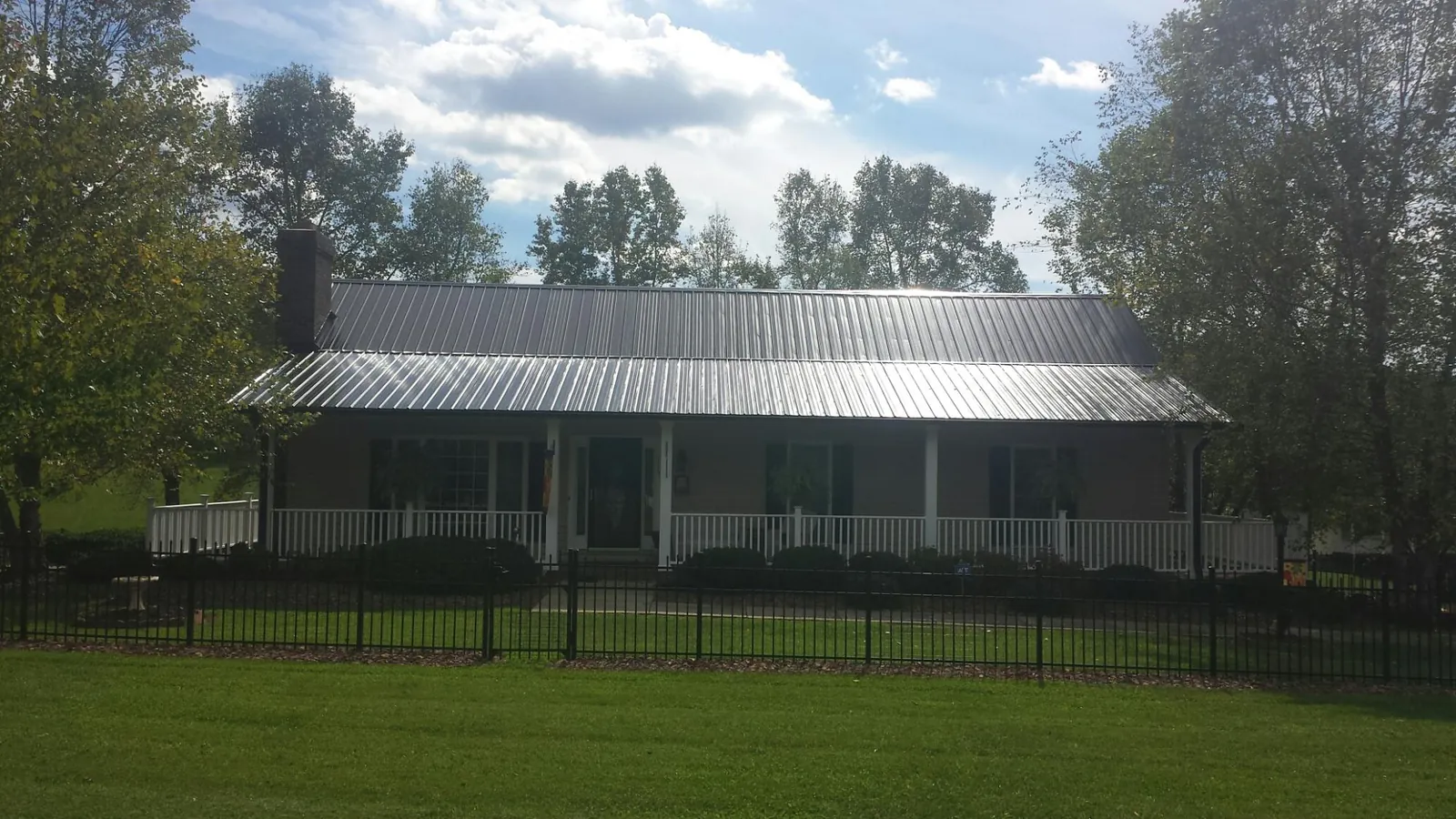 Gray metal roof on a brick ranch with a full width front porch — Gutter Guard Installation work by our crew in Sachse