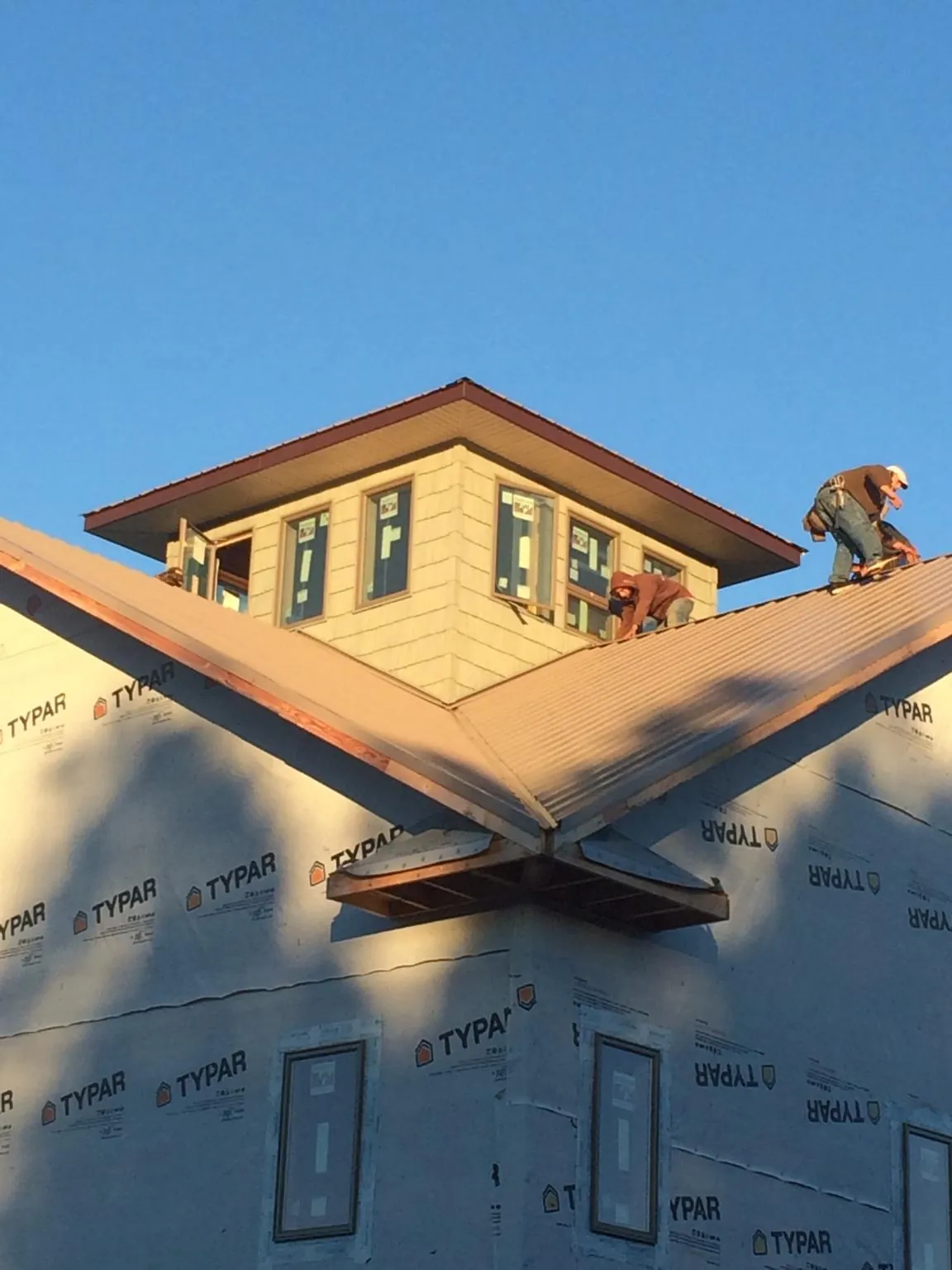 Roofers working around a rooftop cupola on a new metal roof at sunset — Roof Waterproofing in Sachse by Roofing Brothers